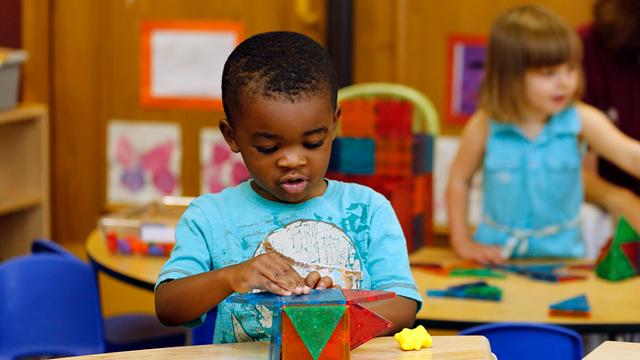 A small child plays with a toy at a table.